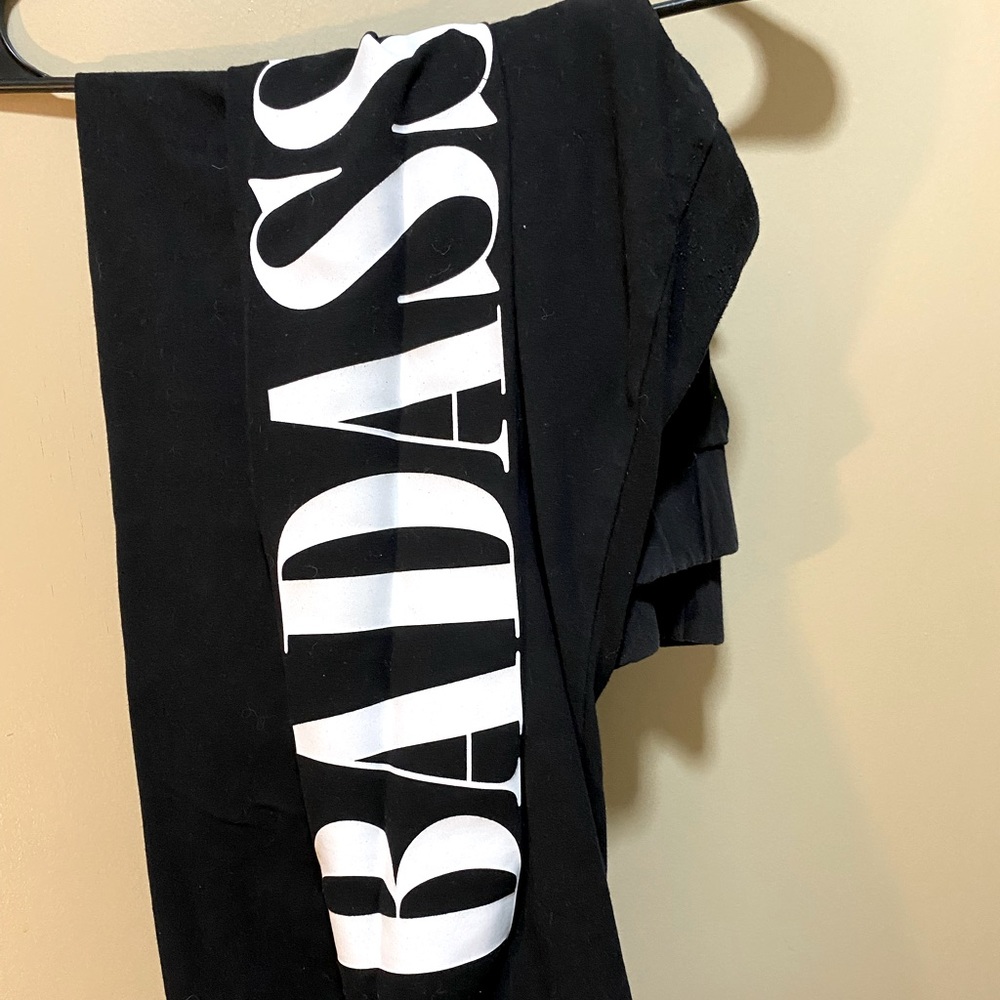 Size 3 torrid leggings, long, black, “bada**” down one leg in white writing.